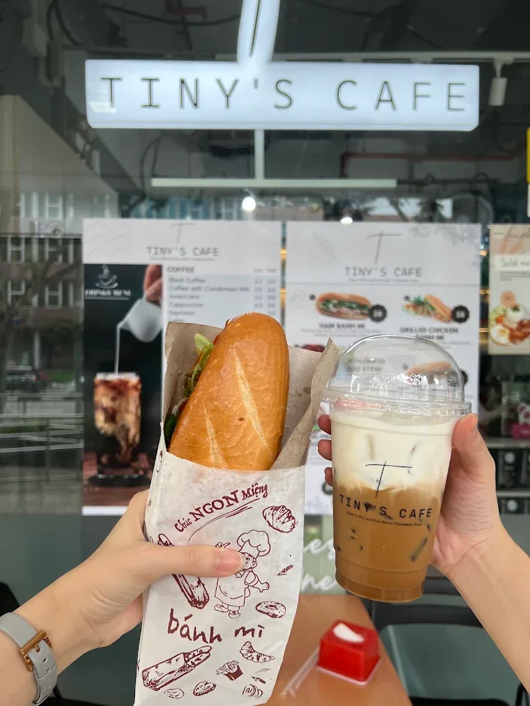 Holding a bánh mì and an iced Tiny's Cafe coffee
